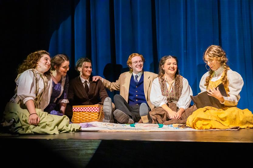 Students sit onstage during Little Women